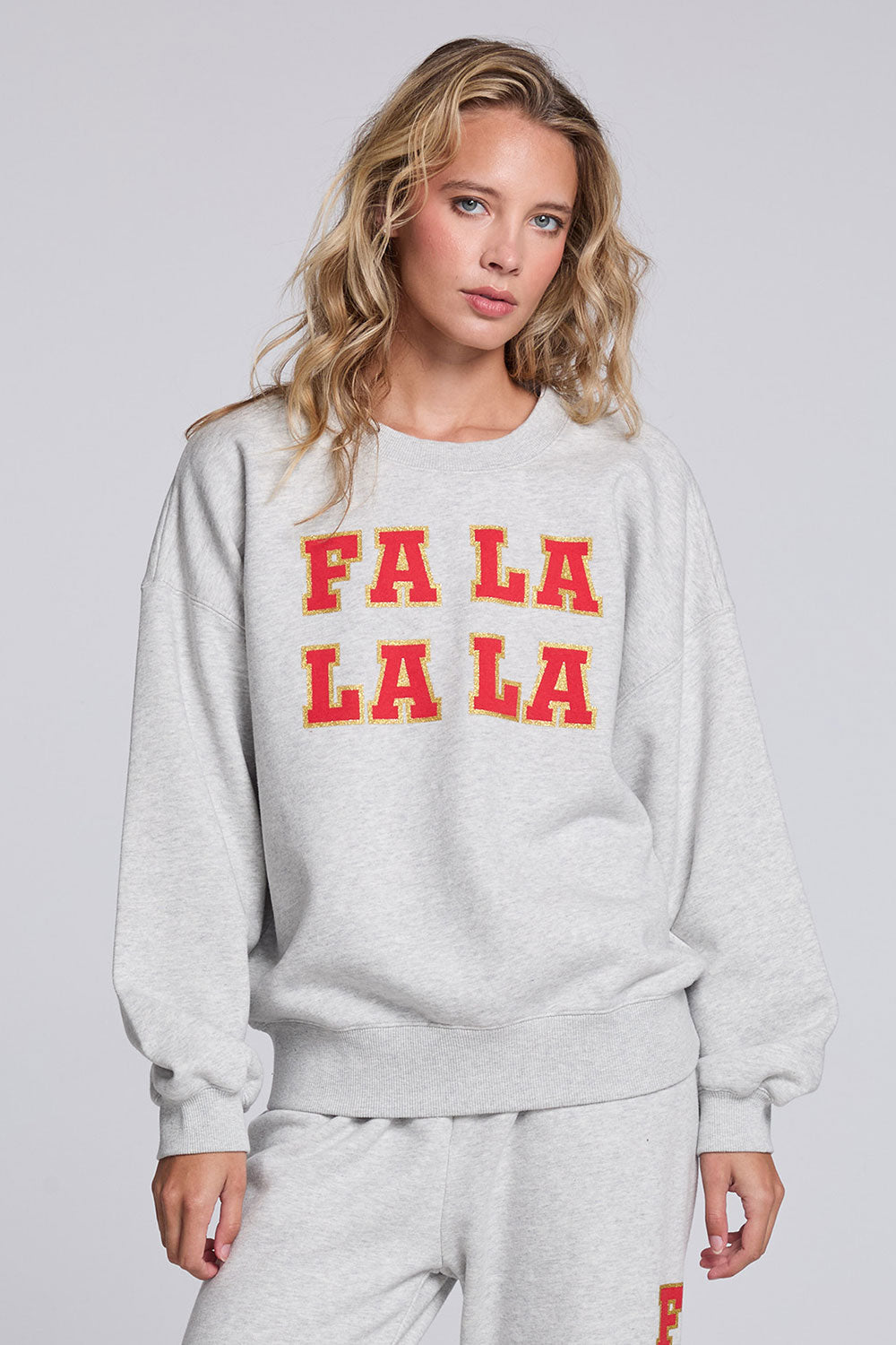 Model wearing Chaser's Fa La La La Pullover in Heather Grey with oversized red Fa La La La lettering, front view