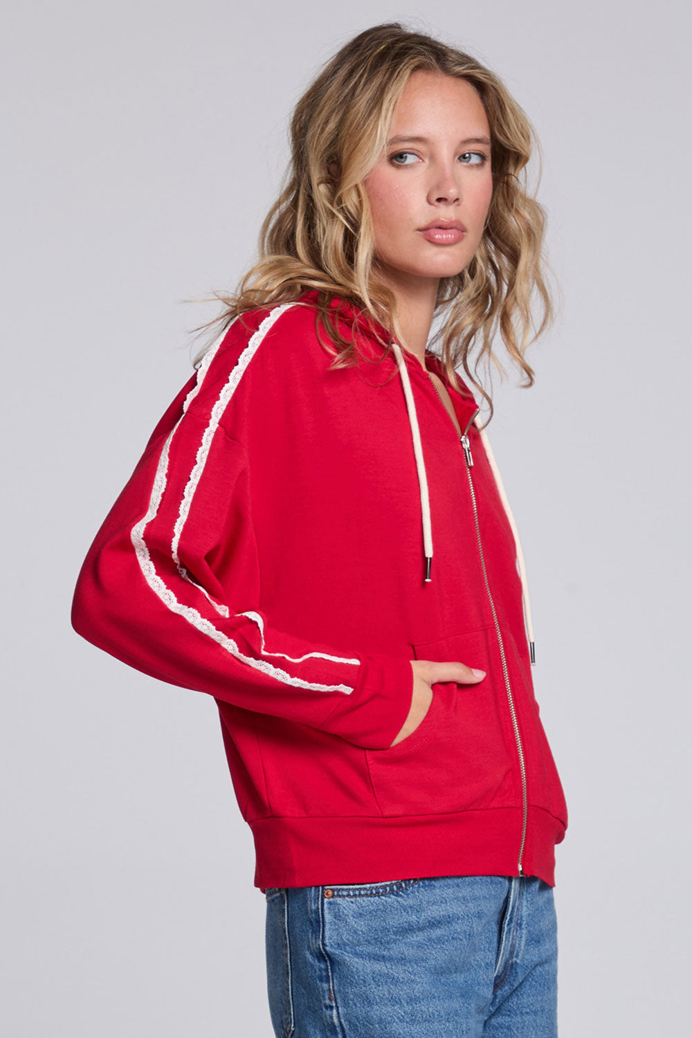 Model wearing Chaser's Cherry Bomb Emily Zip-Up in Cherry Bomb red hooded zip-up with contrast sleeve stripes, angled view