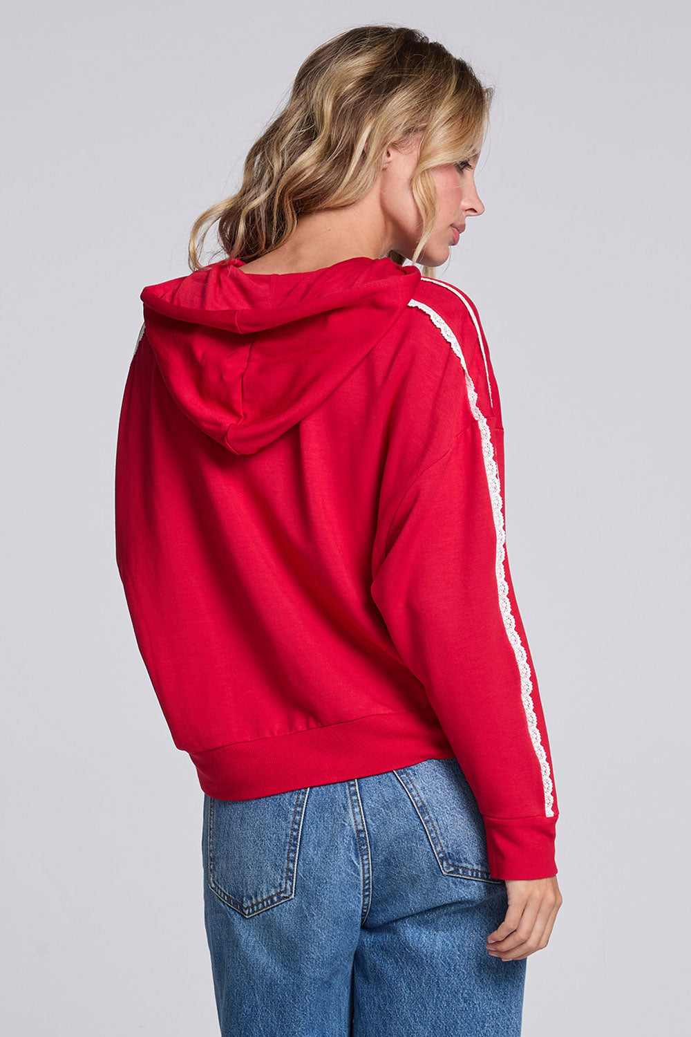 Model wearing Chaser's Cherry Bomb Emily Zip-Up in Cherry Bomb red hooded zip-up with contrast sleeve stripes, back view
