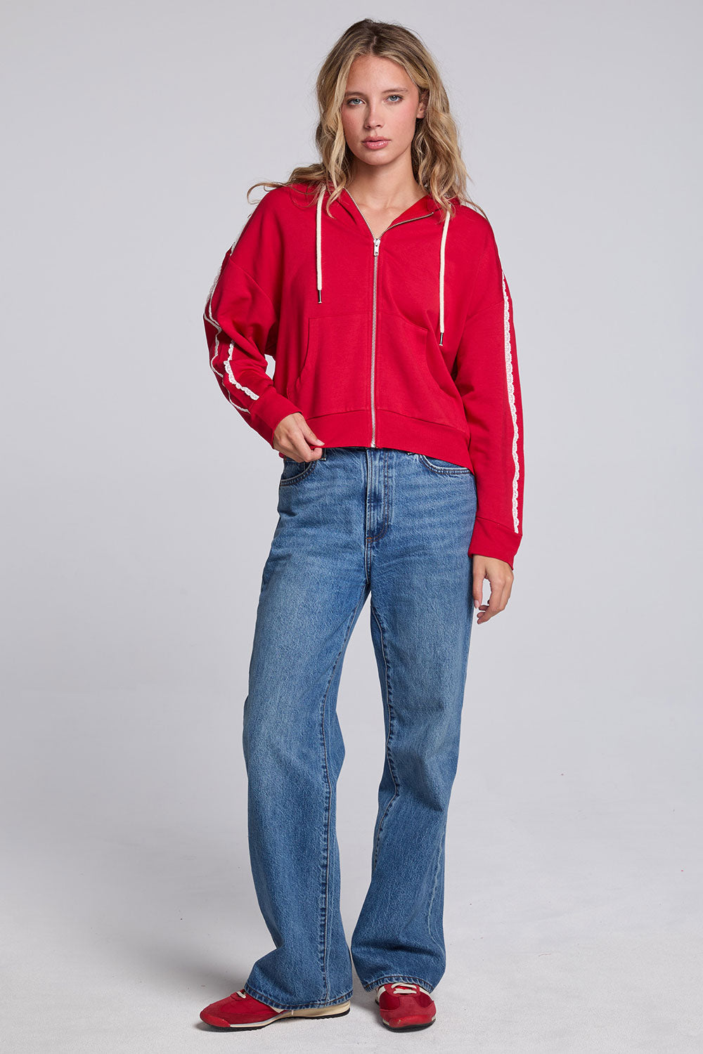Model wearing Chaser's Cherry Bomb Emily Zip-Up and matching Delilah Track Pants in Cherry Bomb with contrast stripes, full-body view