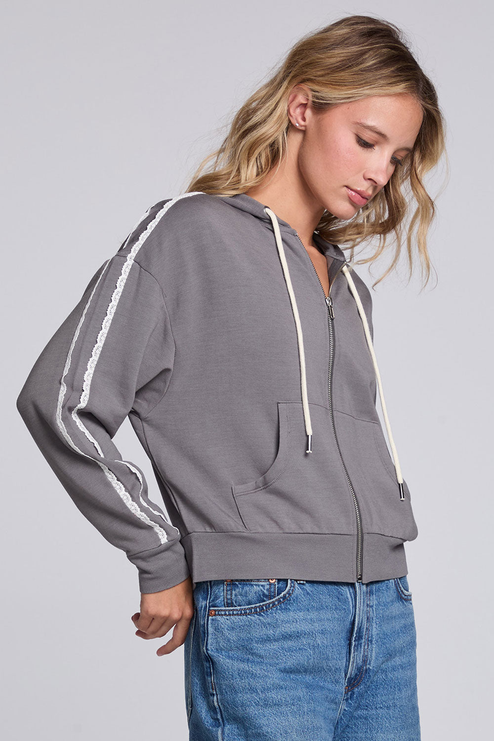 Model wearing Chaser's Soft Graphite Emily Zip-Up in Soft Graphite grey hooded zip-up with contrast sleeve stripes, angled view