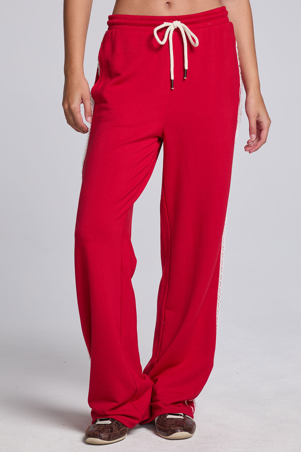 Model wearing Chaser's Cherry Bomb Delilah Track Pants in Cherry Bomb red wide-leg track pants with contrast side stripes, front view
