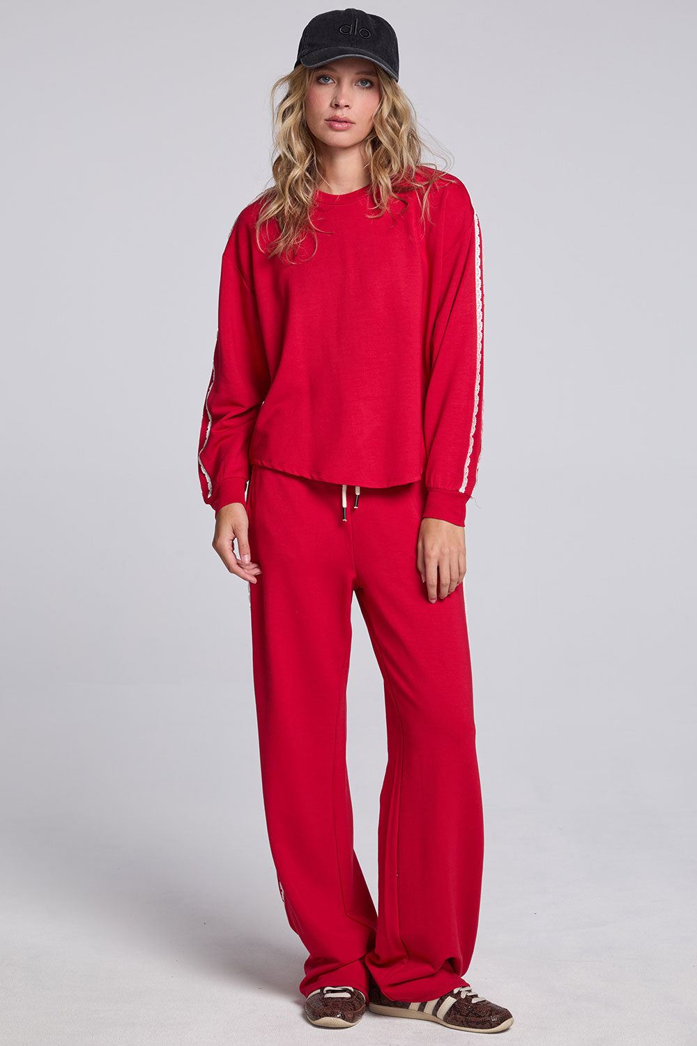 Model wearing Chaser's Cherry Bomb Delilah Track Pants and matching Anastasia Long Sleeve in Cherry Bomb with contrast stripes, full-body view