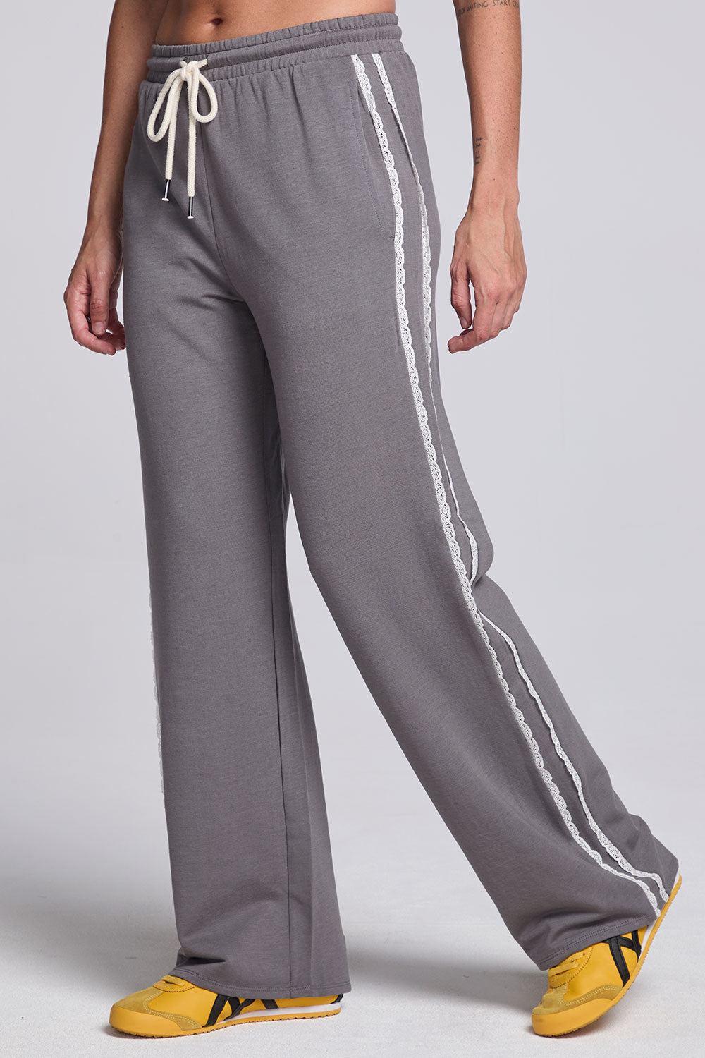 Model wearing Chaser's Soft Graphite Delilah Track Pants in Soft Graphite grey wide-leg track pants with contrast side stripes, angled view