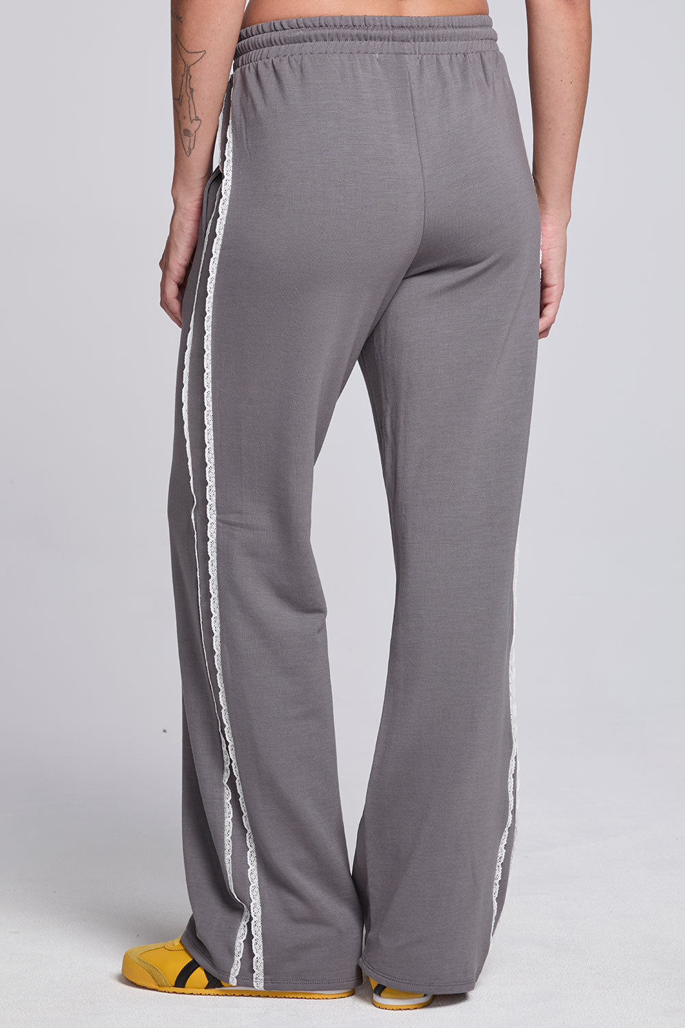 Model wearing Chaser's Soft Graphite Delilah Track Pants in Soft Graphite grey wide-leg track pants with contrast side stripes, back view