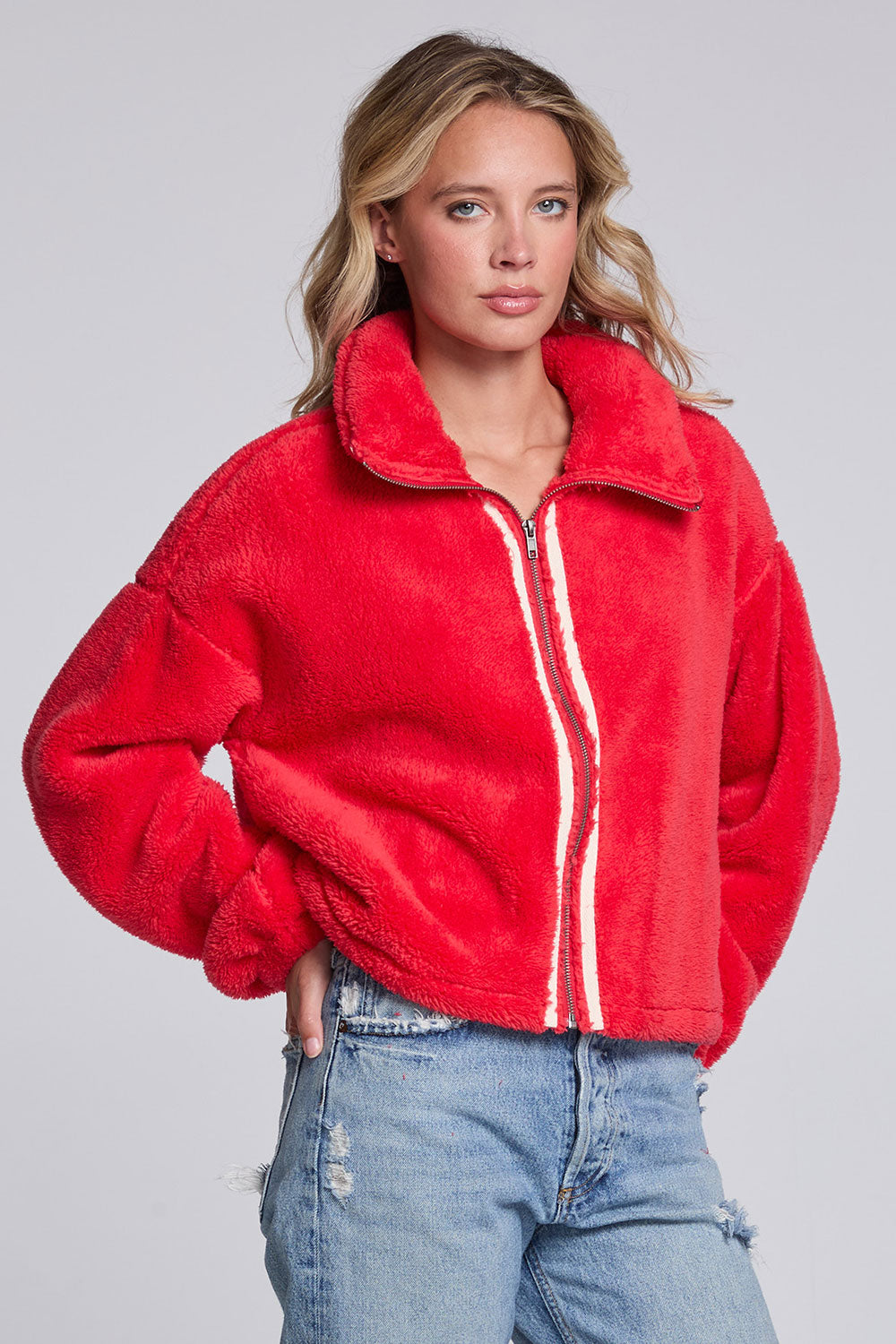 Model wearing Chaser's Cherry Zip-Up in Cherry Bomb red plush zip-up jacket with high collar, angled view