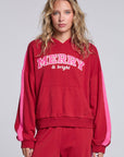 Model wearing Chaser's Merry and Bright Hoodie in Cranberry Velvet with varsity-style Merry and Bright artwork, front view