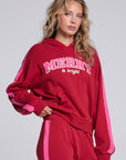 Model wearing Chaser's Merry and Bright Hoodie in Cranberry Velvet with varsity-style Merry and Bright artwork, angled view