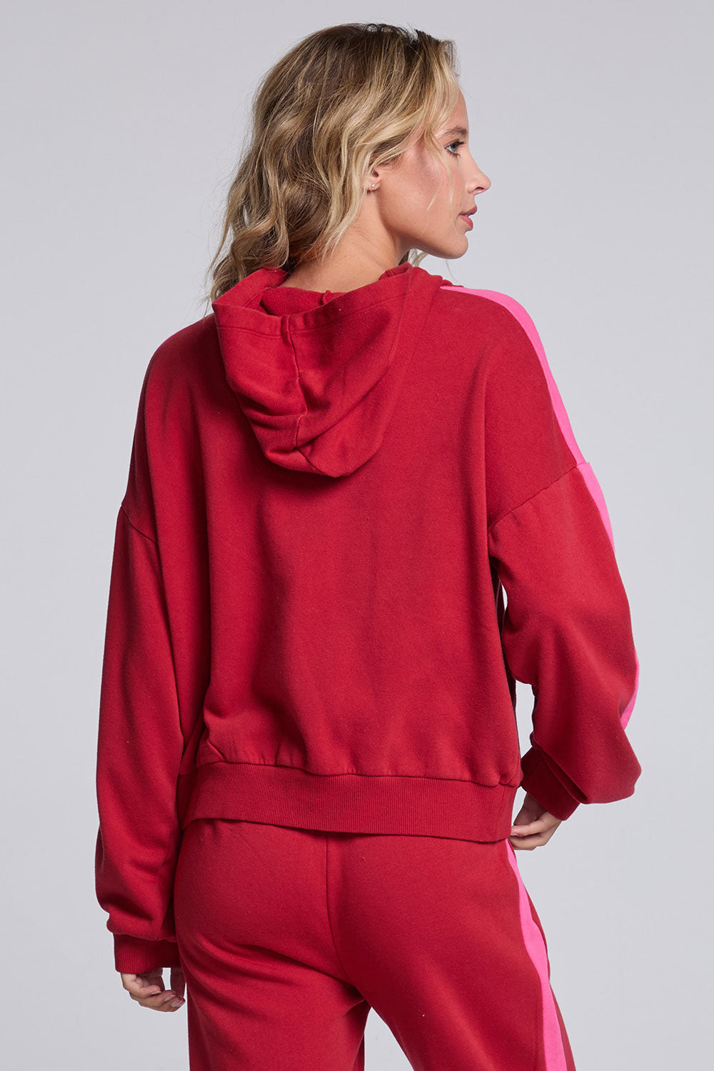 Model wearing Chaser's Merry and Bright Hoodie in Cranberry Velvet with varsity-style Merry and Bright artwork, back view