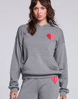 Model wearing Chaser's Dual Tone Heart Hoodie in Streaky with a single red heart, front view