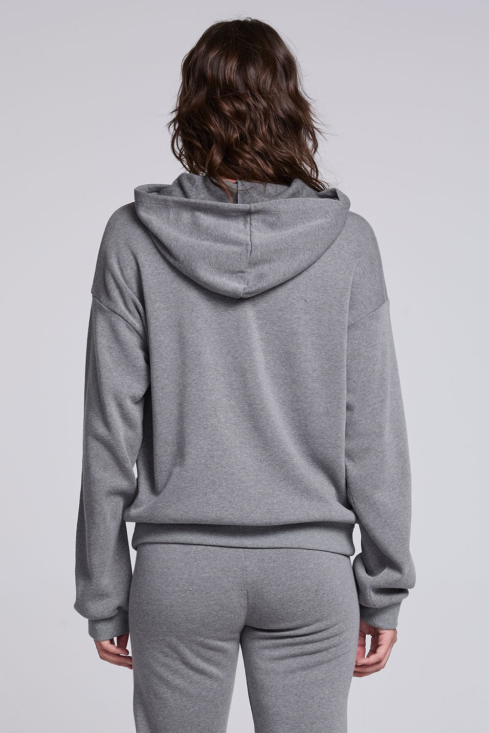 Model wearing Chaser's Dual Tone Heart Hoodie in Streaky with a single red heart, back view
