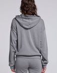 Model wearing Chaser's Dual Tone Heart Hoodie in Streaky with a single red heart, back view