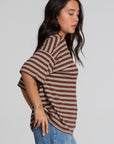 Side view of a woman wearing the Chaser Peri Nutty Brown Stripe Tee and blue jeans on a neutral background