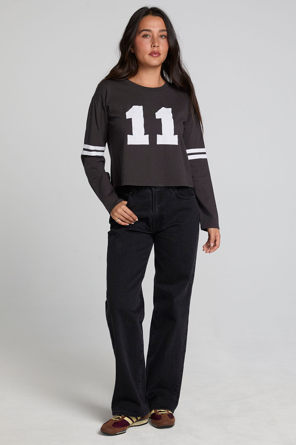 A full body front view of a woman wearing the Chaser 11 Long Sleeve on a neutral background