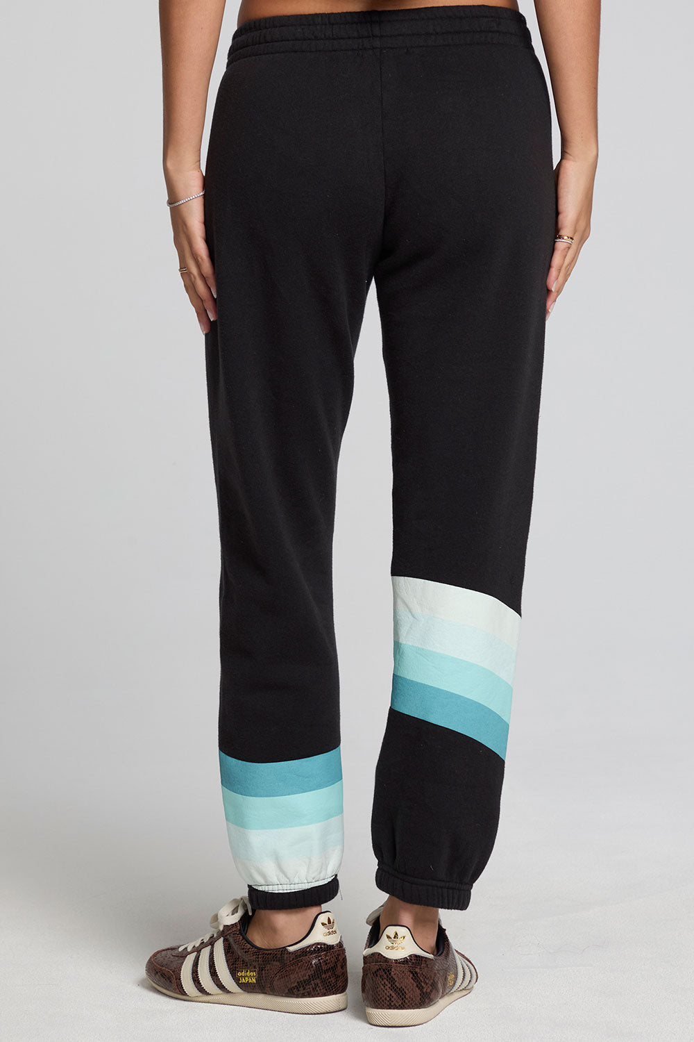 Back view of a woman wearing the Chaser Ada Black Jogger on a neutral background with arms at sides and sneakers