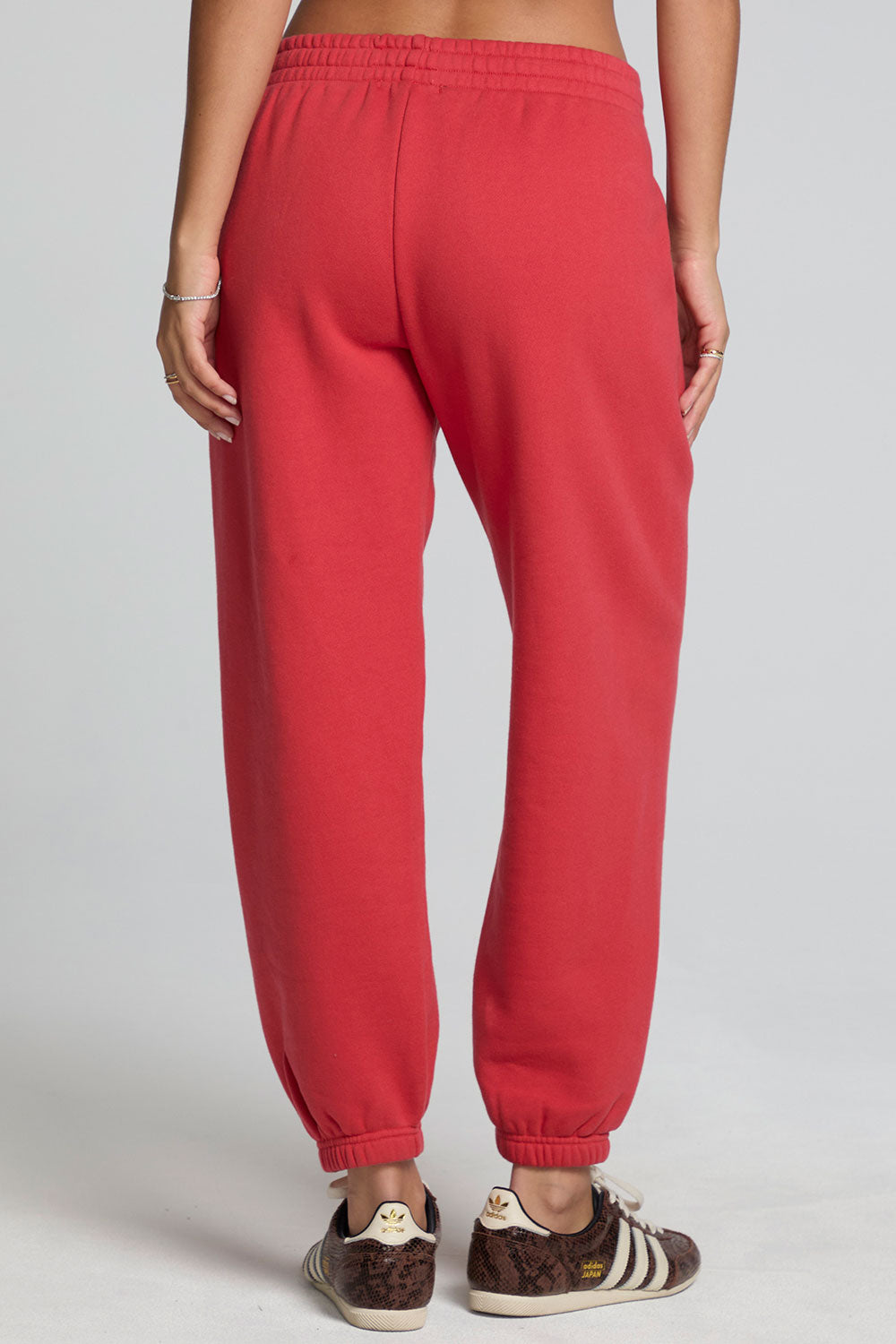 Back view of a woman wearing the Chaser Ada Dry Red Jogger on a neutral background with arms at sides and brown sneakers 