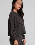 Side view of a woman wearing the Chaser Chaser Allover Mini Stars Long Sleeve and matching black pants on a neutral background