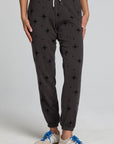 Front view of a woman wearing the Chaser  Allover Mini Stars Pants on a neutral background with hands at sides and sneakers