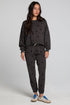 Full body front view of a woman wearing the Chaser Allover Mini Stars Pants set on a neutral background with hands at sides and sneakers
