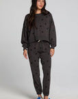 Full body front view of a woman wearing the Chaser Allover Mini Stars Pants set on a neutral background with hands at sides and sneakers