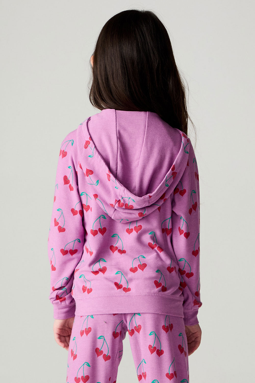 Back view of a girl wearing the Chaser Allover Sweethearts Girls Hoodie on a neutral background with pants