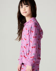 Side view of a girl wearing the Chaser Allover Sweethearts Girls Hoodie on a neutral background with matching pants