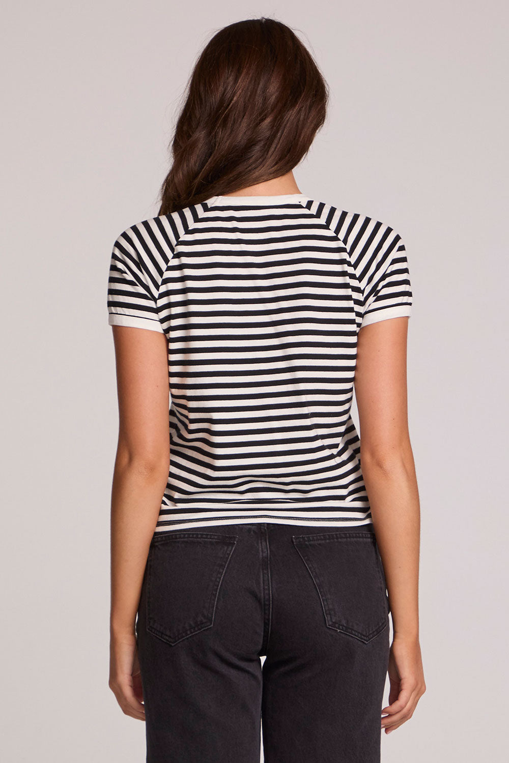 Back view of a woman wearing the Chaser Bisous Tee on a neutral background with pants 