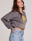 Side angle view of a woman wearing the Chaser Blondie Live Cropped Sweatshirt on a neutral background with hand in pocket