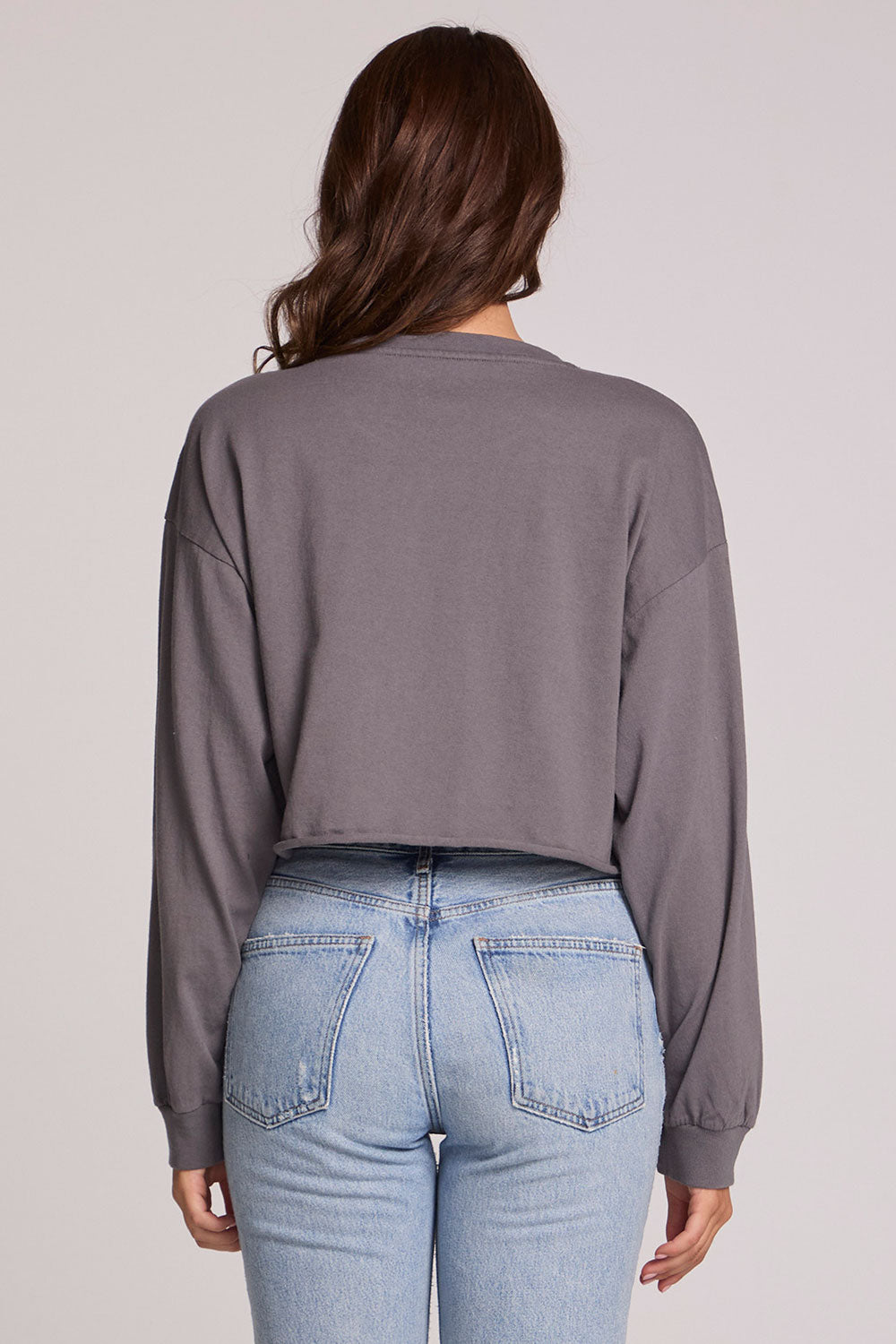 Back view of a woman wearing the Chaser Blondie Live Cropped Sweatshirt on a neutral background with hands at sides