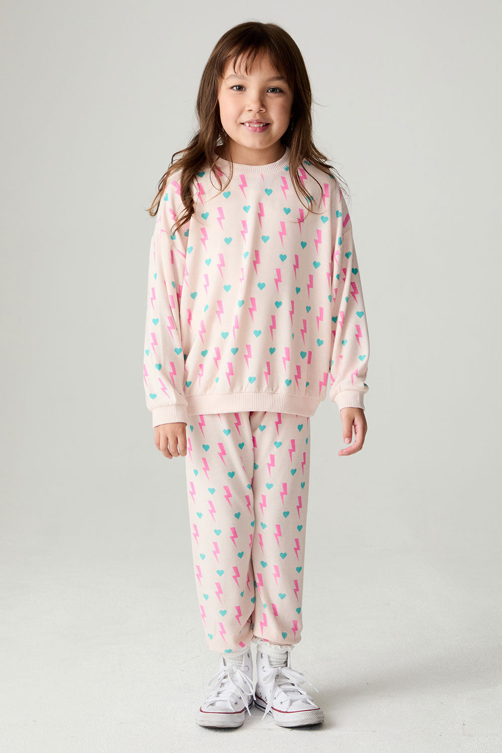 A full body front view of a girl wearing the Chaser Bolt Hearts Girls Jogger on a neutral background