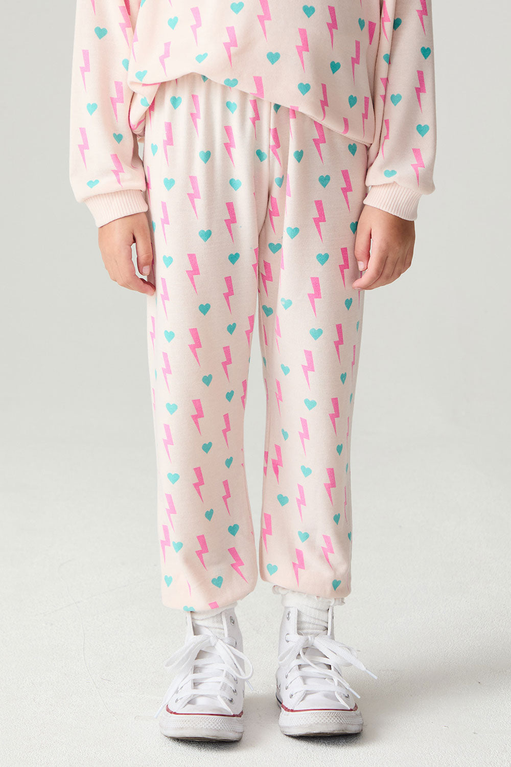 Front view of a girl wearing the Chaser Bolt Hearts Girls Jogger on a neutral background with matching long sleeve top