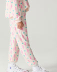 Side view of a girl wearing the Chaser Bolt Hearts Girls Jogger on a neutral background with long sleeve top
