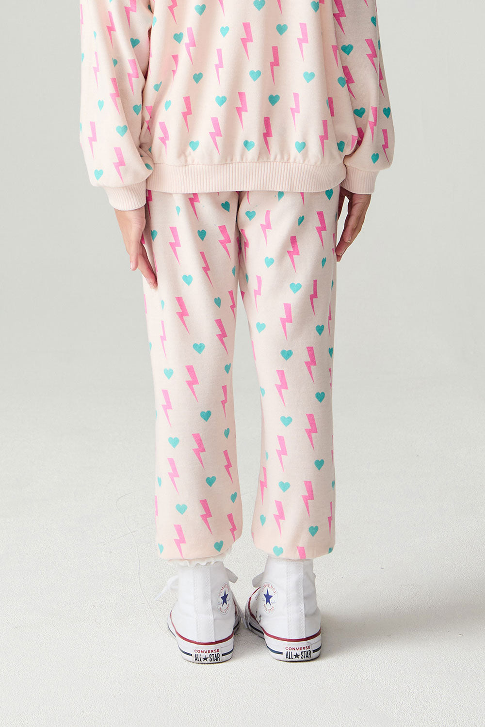 Back  view of a girl wearing the Chaser Bolt Hearts Girls Jogger on a neutral background with top