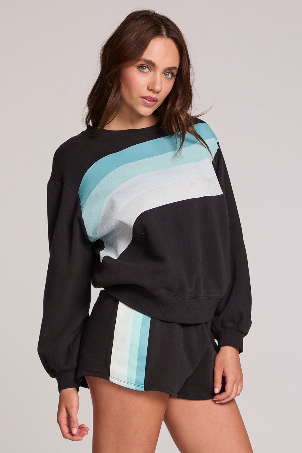 Front view of a woman wearing the Chaser  Cashbah Black Pullover on a neutral background with matching shorts