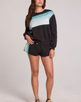 Full body front view of a woman wearing the Chaser Cashbah Black Pullover on a neutral background with matching black shorts and shoes