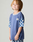 Side view of a boy wearing the Chaser Smileys Boys Tee on a neutral background with matching pants