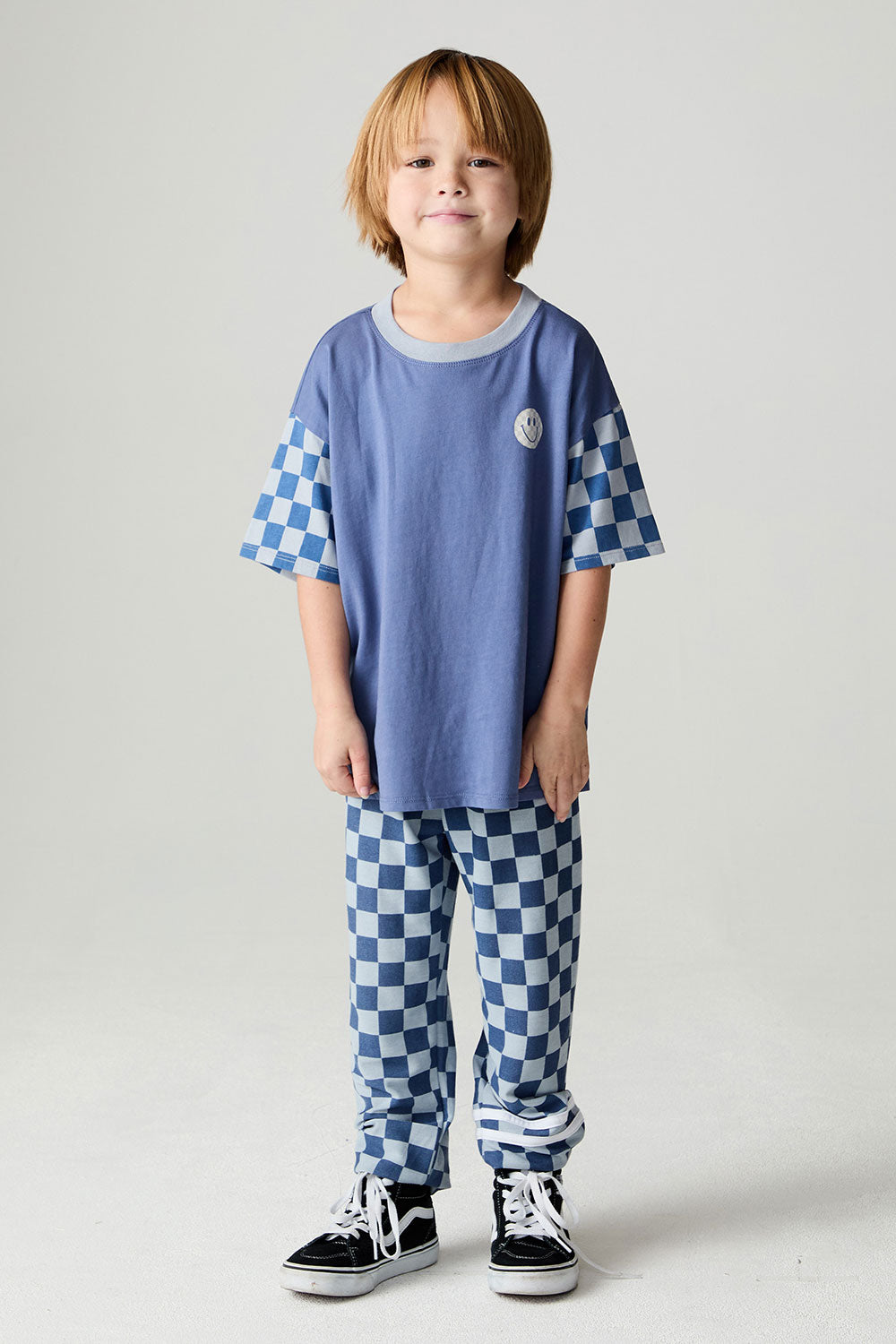 A full body front view of a boy wearing the Chaser Smileys Boys Tee on a neutral background