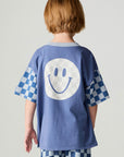 Back view of a boy wearing the Chaser Smileys Boys Tee on a neutral background with pants