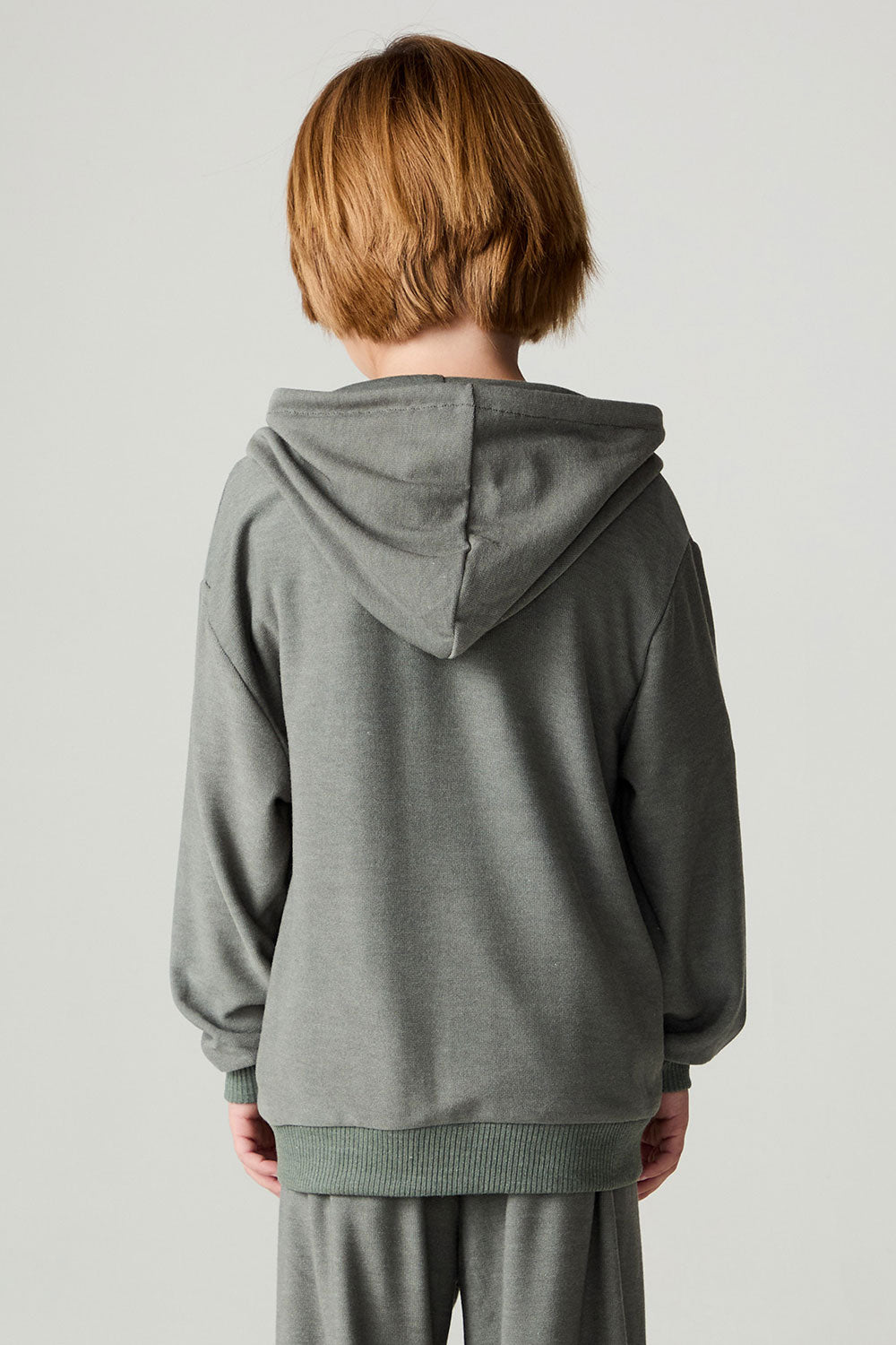 Back view of a boy wearing the Chaser Cool Camo Boys Zip Up on a neutral background and pants