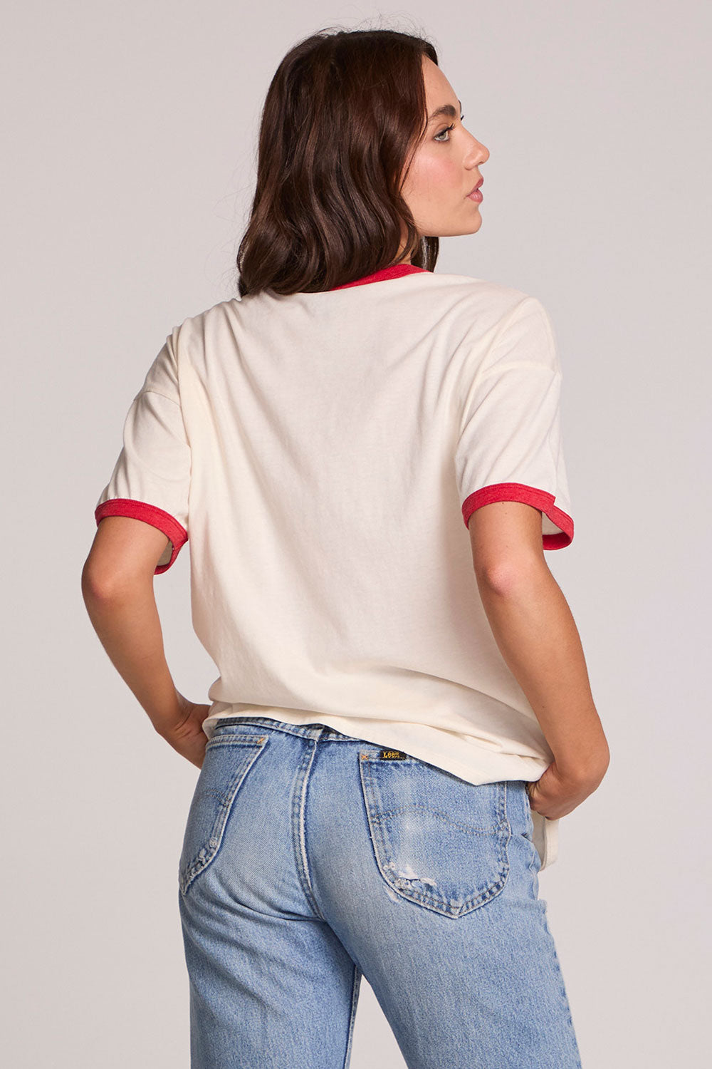 Back view of a woman wearing the Chaser David Bowie Bowie Bolt Tee on a neutral background with jeans