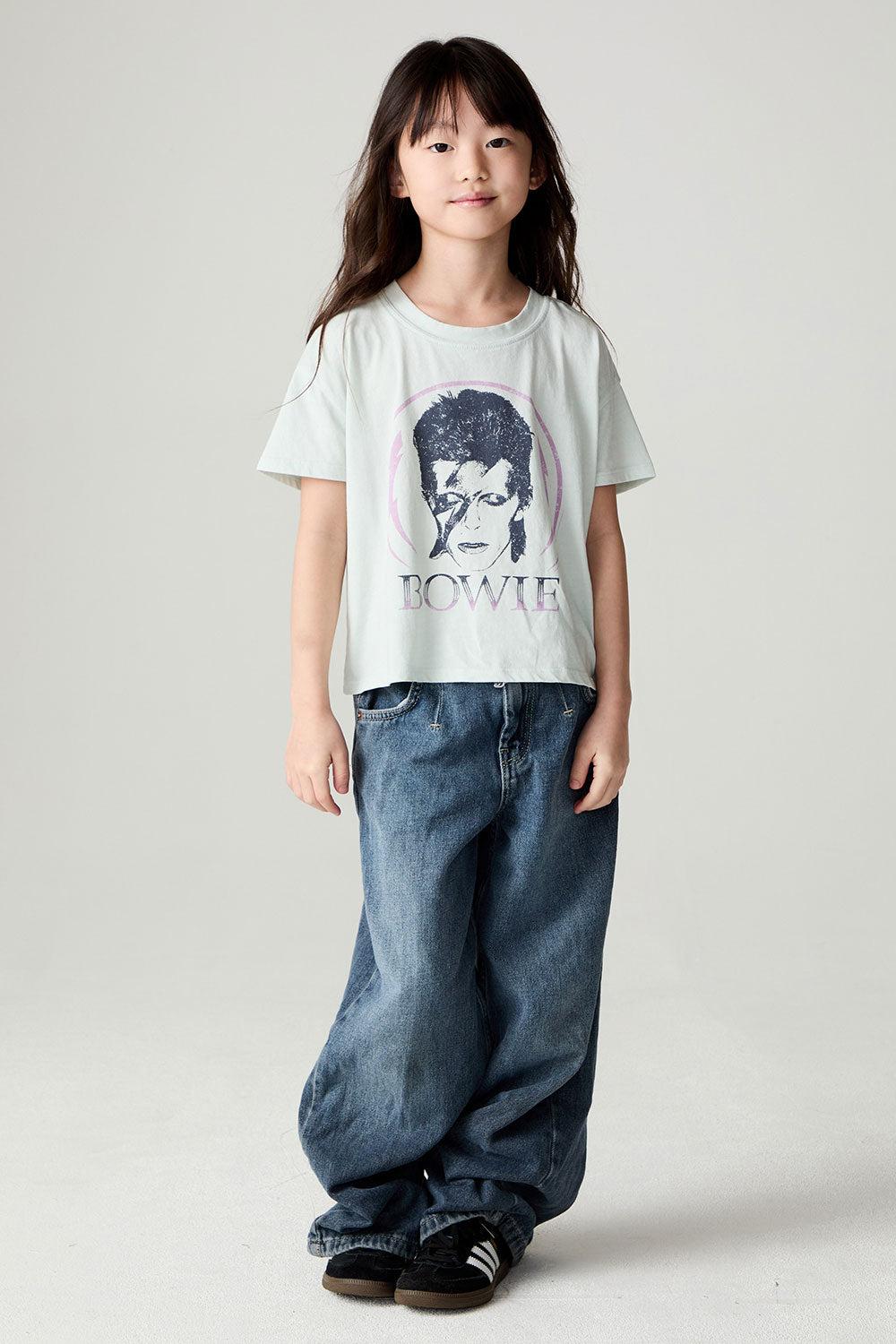 A full body front view of a girl wearing the Chaser David Bowie Stars Bowie Girls Tee on a neutral background
