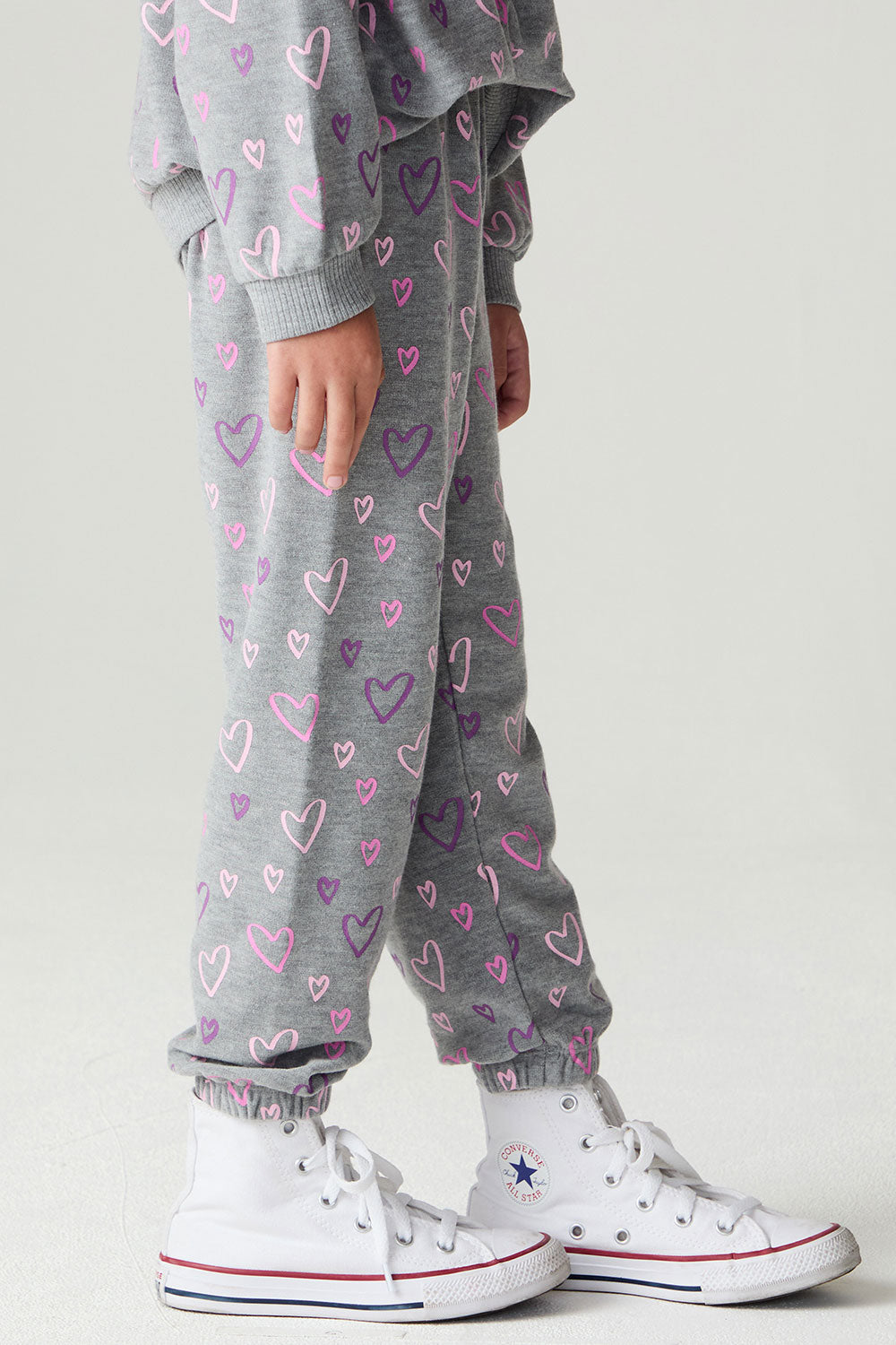 Side view of a girl wearing the Chaser Ditsy Hearts Girls Jogger on a neutral background with shirt