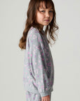 Side view of a girl wearing the Chaser Ditsy Hearts Girls Tee and matching pants on a neutral background