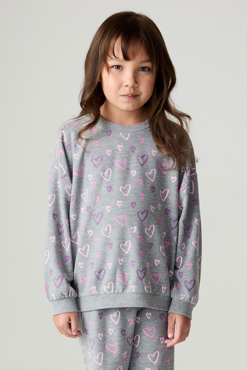 Front view of a girl wearing the Chaser Ditsy Hearts Girls Tee and matching pants on a neutral background with hands down