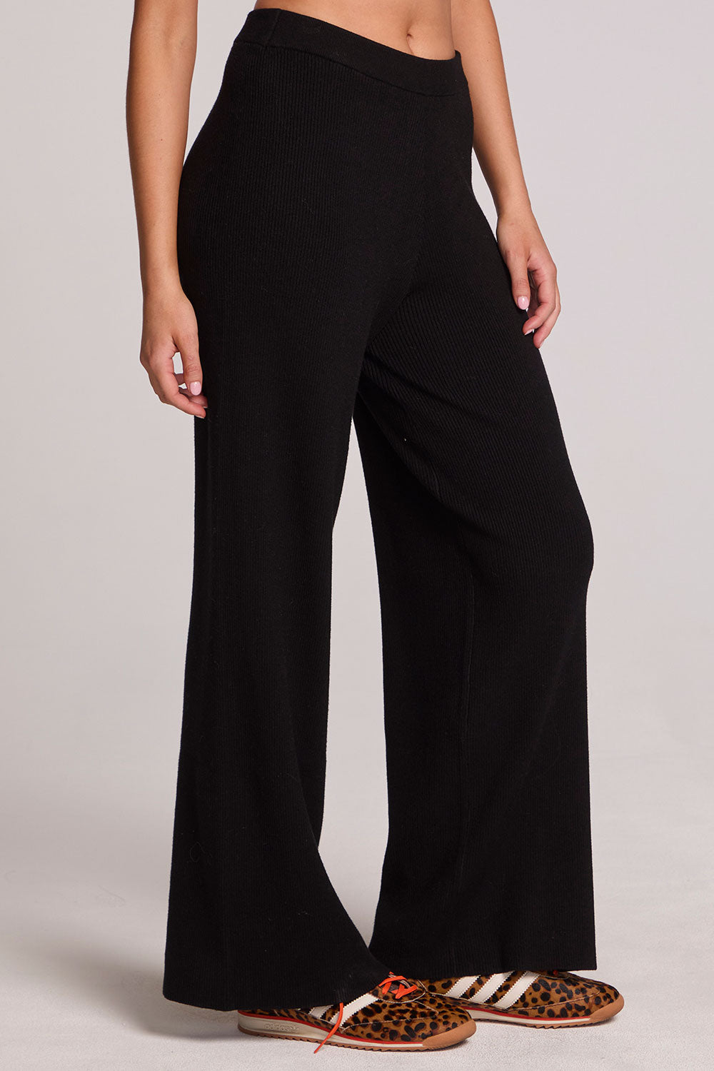Side view of a woman wearing the Chaser Eliza Black Pants and shoes on a neutral background