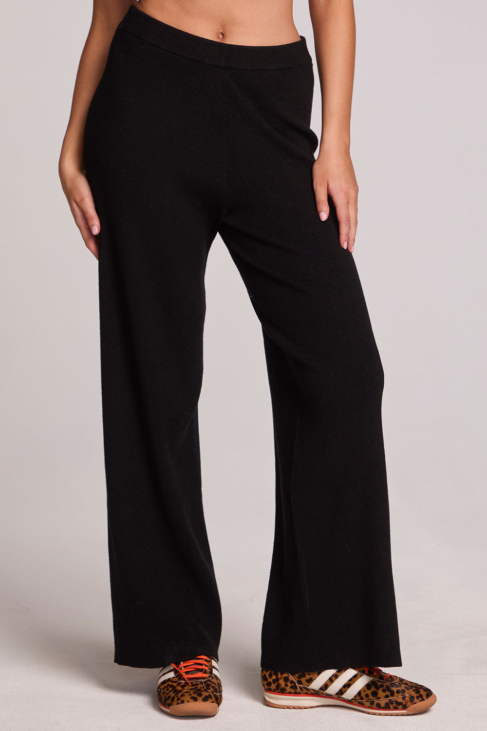 Front view of a woman wearing the Chaser Eliza Black Pants and sneakers on a neutral background