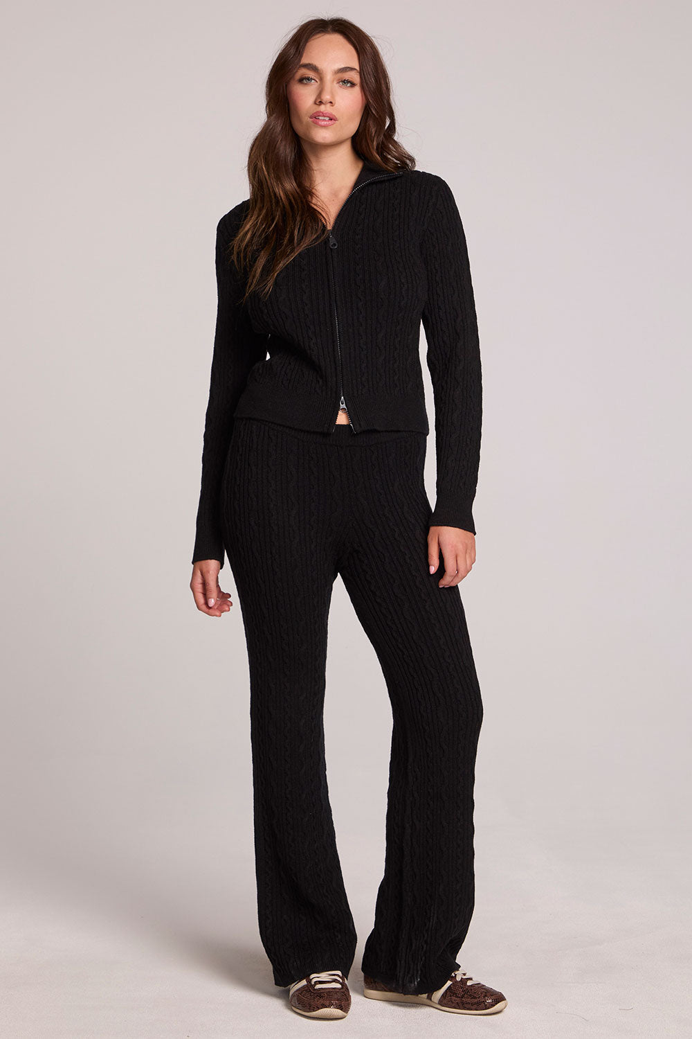 Full body front view of a woman wearing the Chaser Eliza Black Pants and matching zip up on a neutral background