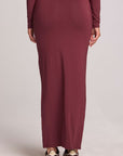 Back view of a woman wearing the Chaser Eloyse Brick Red Skirt on a neutral background with red top