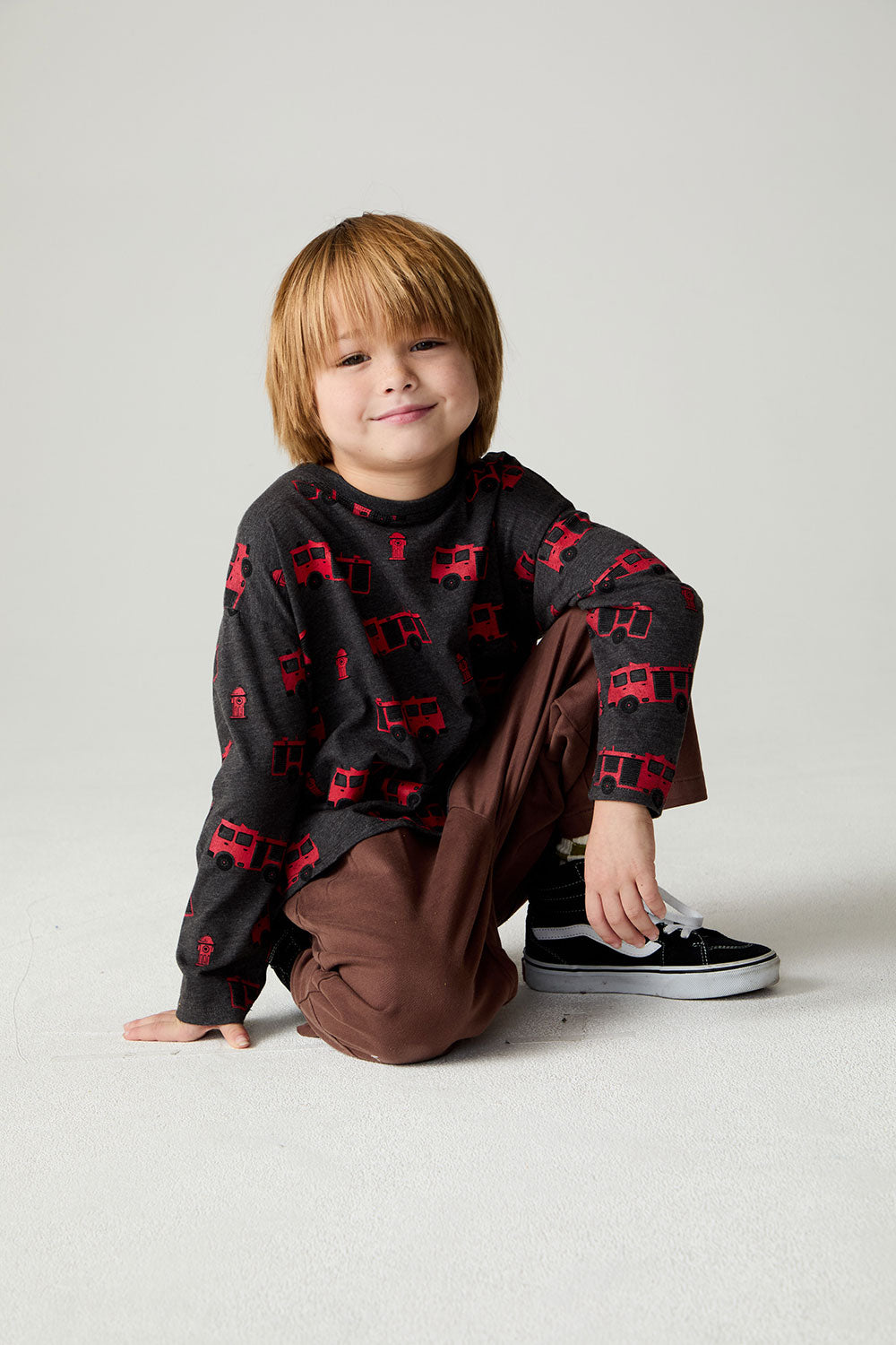 Seated boy wearing the Chaser Fire Trucks Boys Tee on a neutral background