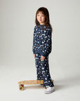 Front view of a girl wearing the Chaser Free Draw Girls Tee and matching pants on a neutral background posing with a skateboard